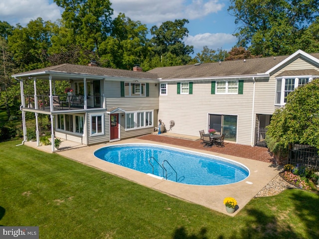 back of property with a lawn, a balcony, and a patio