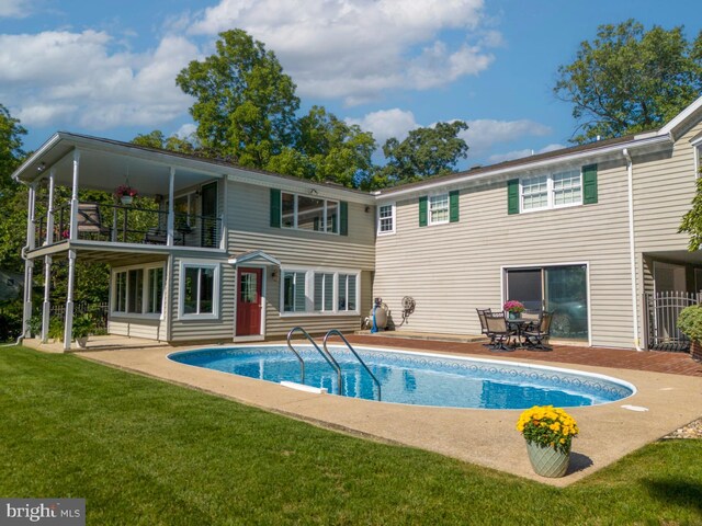 back of house featuring a patio, a balcony, and a yard