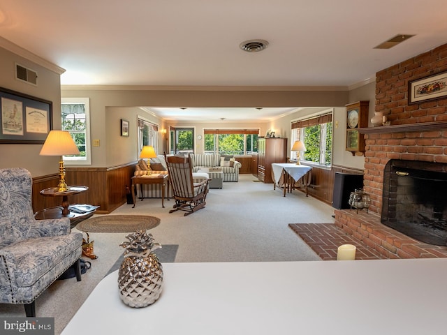 carpeted living room with ornamental molding, a fireplace, and wooden walls