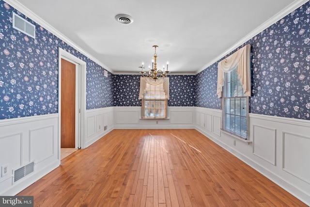 unfurnished dining area featuring light hardwood / wood-style floors, ornamental molding, and a chandelier