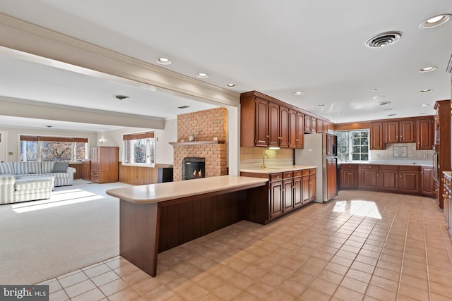 kitchen featuring light carpet, a healthy amount of sunlight, fridge, and a brick fireplace