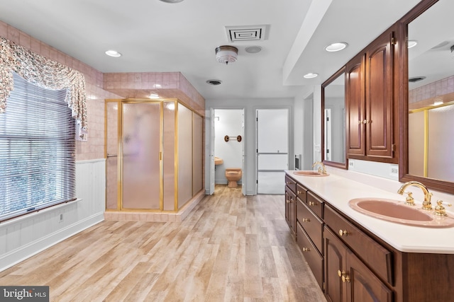 bathroom with toilet, a shower with shower door, hardwood / wood-style floors, and vanity