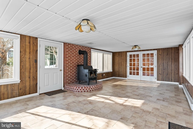 unfurnished sunroom with a wood stove and french doors