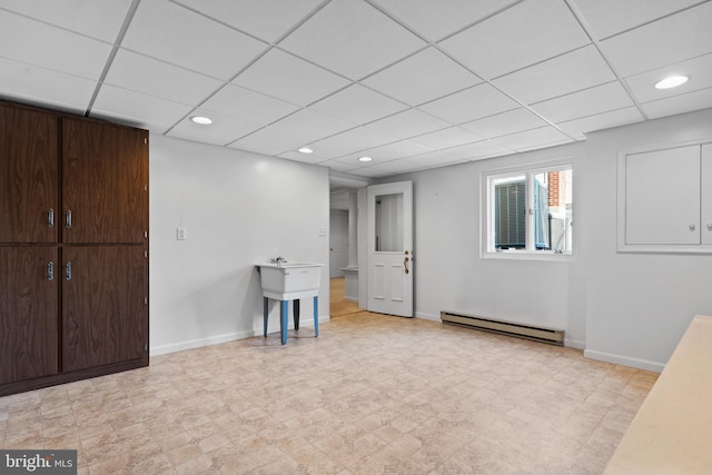 basement with a drop ceiling and a baseboard radiator