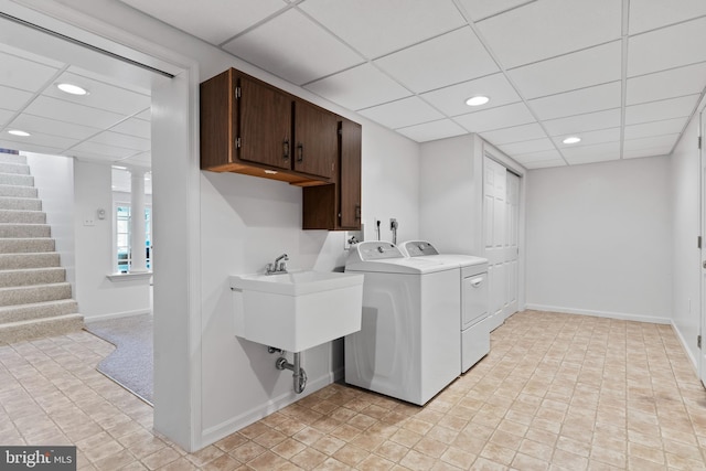 clothes washing area featuring light carpet, sink, washing machine and clothes dryer, and cabinets