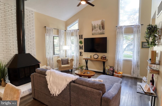 living room with dark hardwood / wood-style flooring, high vaulted ceiling, a wood stove, and ceiling fan