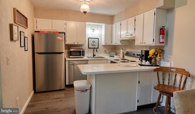 kitchen with stainless steel appliances, white cabinetry, sink, kitchen peninsula, and a breakfast bar area