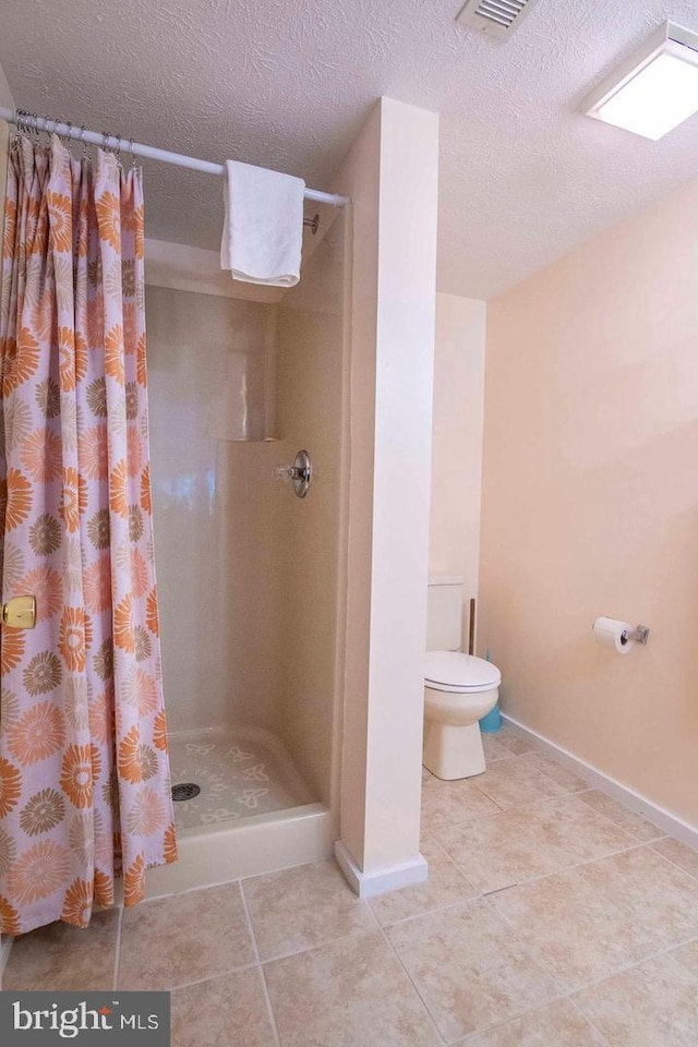 bathroom featuring toilet, tile patterned flooring, a textured ceiling, and a shower with shower curtain