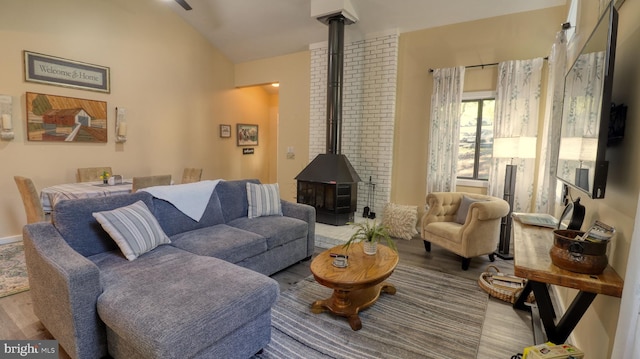 living room with hardwood / wood-style floors, a wood stove, and lofted ceiling