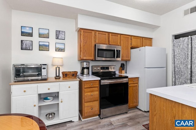 kitchen with light hardwood / wood-style flooring and appliances with stainless steel finishes