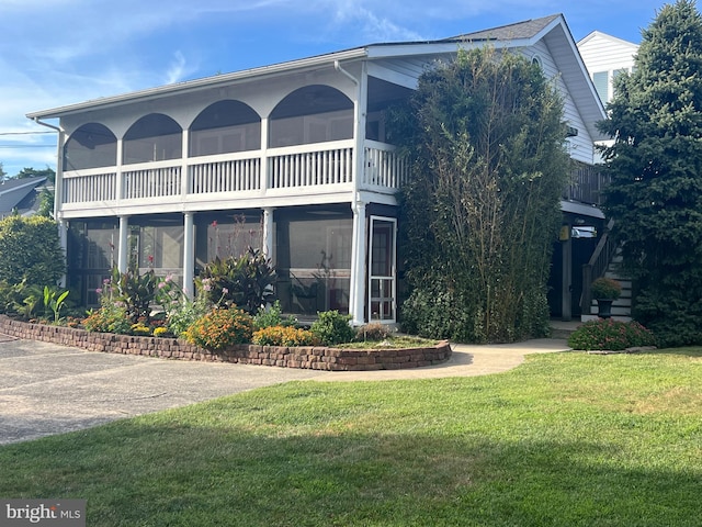 rear view of property with a sunroom and a yard