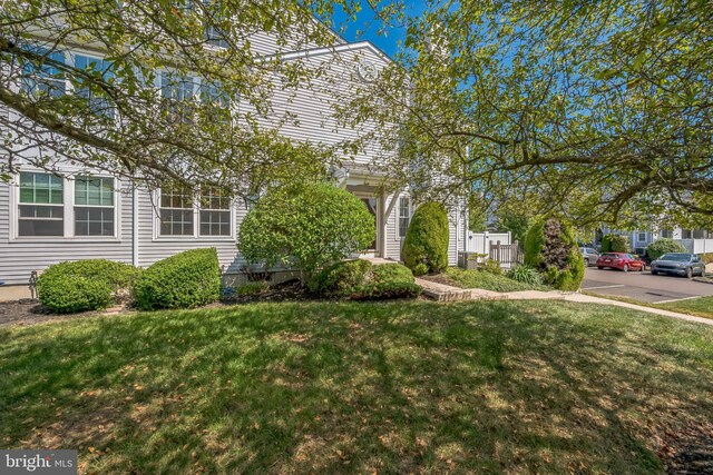 view of property hidden behind natural elements featuring a front lawn