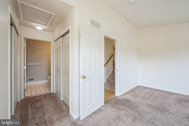 corridor with attic access, visible vents, and carpet flooring