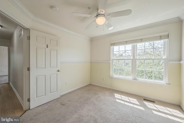 empty room featuring carpet flooring, ceiling fan, and crown molding