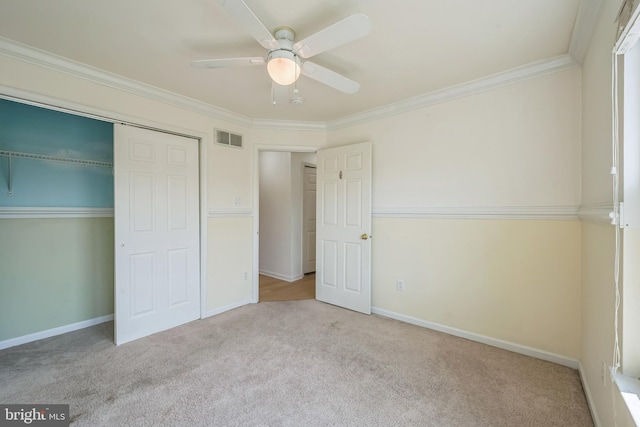 unfurnished bedroom with light carpet, ornamental molding, ceiling fan, and a closet