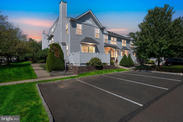 view of front of property featuring uncovered parking, a front yard, and a chimney