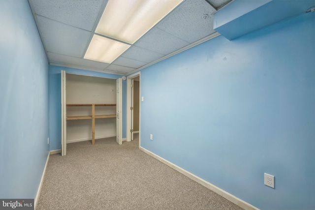 unfurnished bedroom with a closet, carpet flooring, baseboards, and a drop ceiling