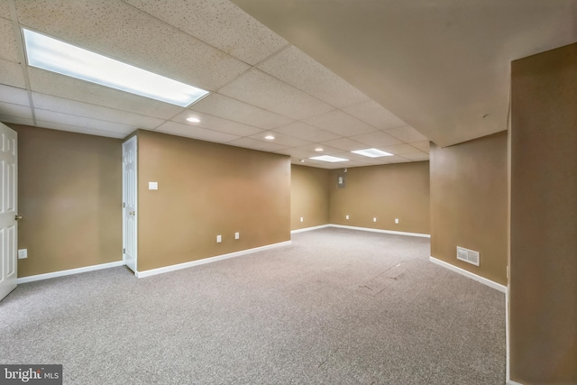 basement featuring a paneled ceiling and carpet flooring