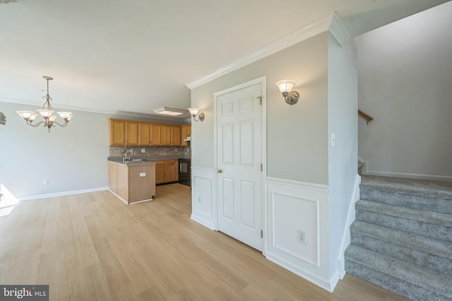 kitchen with decorative backsplash, ornamental molding, hanging light fixtures, light wood-style floors, and a sink