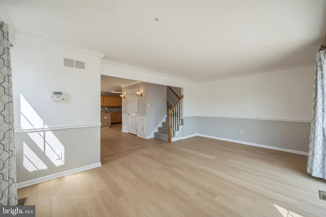 spare room with visible vents, baseboards, stairway, crown molding, and light wood-style floors