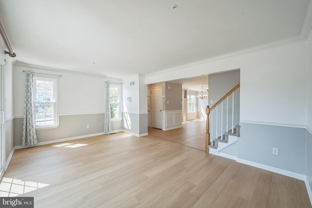 spare room with a notable chandelier, visible vents, ornamental molding, stairway, and light wood finished floors