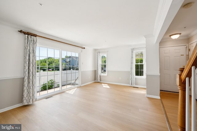 empty room featuring ornamental molding, light wood-type flooring, visible vents, and baseboards