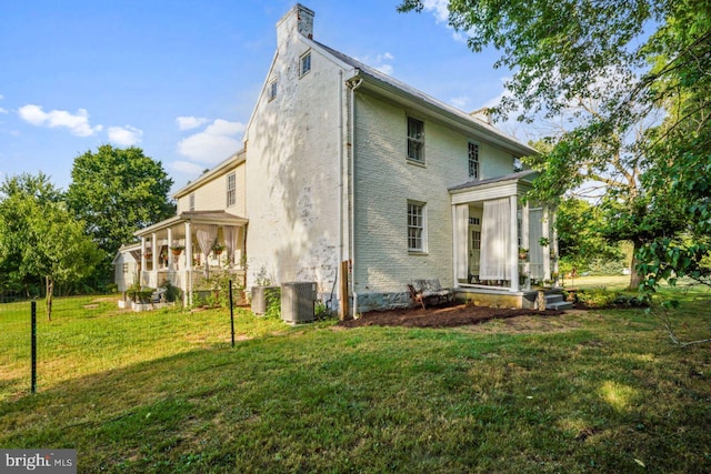 back of property featuring a sunroom and a lawn