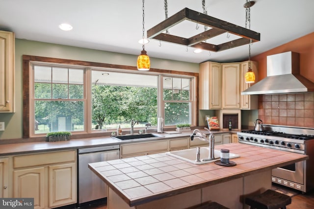 kitchen featuring stainless steel appliances, tile counters, a center island, sink, and wall chimney exhaust hood