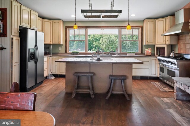 kitchen featuring wall chimney exhaust hood, a center island, stainless steel appliances, and dark hardwood / wood-style floors