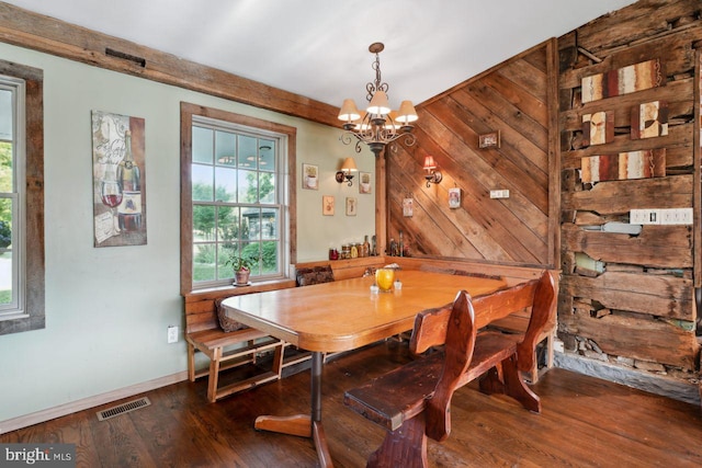 dining room featuring a chandelier, wooden walls, and dark hardwood / wood-style flooring