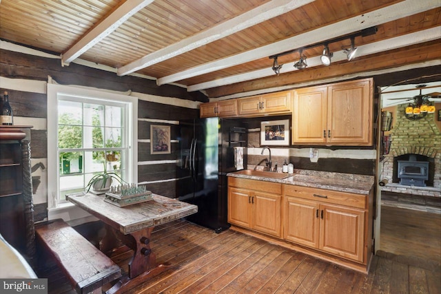 kitchen with a brick fireplace, wood ceiling, sink, black refrigerator, and dark hardwood / wood-style floors