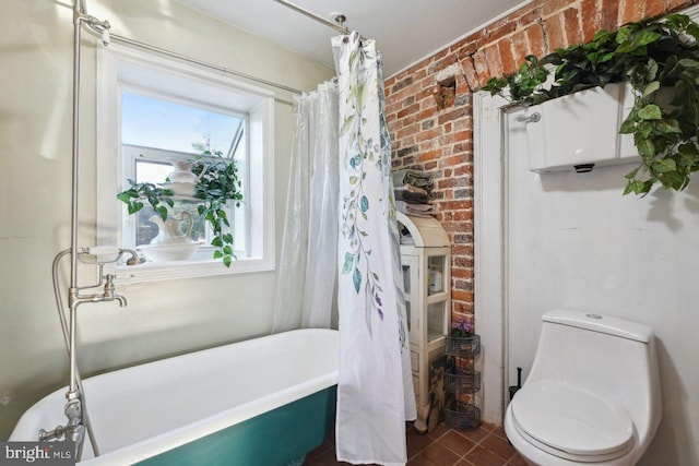 bathroom featuring brick wall, toilet, a healthy amount of sunlight, and a bathing tub