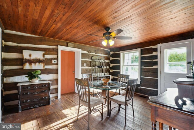 dining space with rustic walls, wood-type flooring, wood ceiling, and ceiling fan