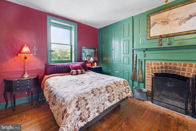 bedroom with dark hardwood / wood-style floors and a fireplace