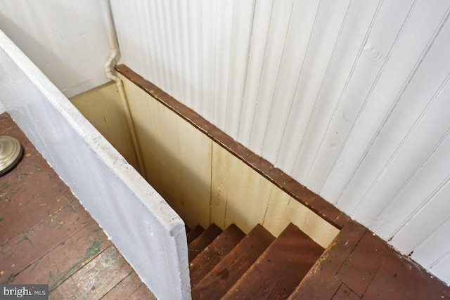 stairway featuring wooden walls