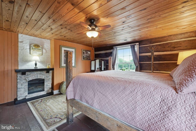 bedroom featuring wooden walls, a fireplace, hardwood / wood-style floors, wood ceiling, and ceiling fan