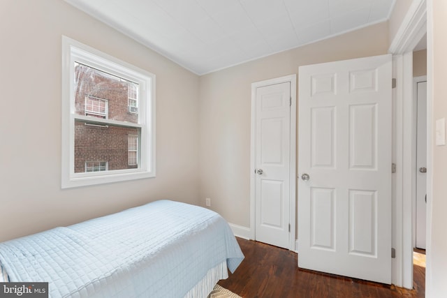 bedroom with multiple windows and dark hardwood / wood-style floors