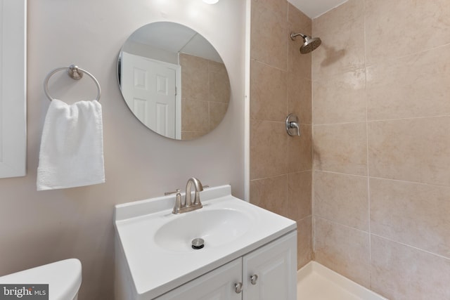 bathroom with tiled shower, vanity, and toilet