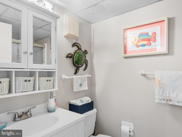 bathroom with a drop ceiling, vanity, and toilet