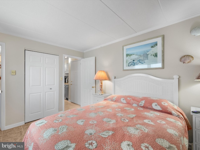 bedroom with ornamental molding, a closet, light tile patterned flooring, and baseboards