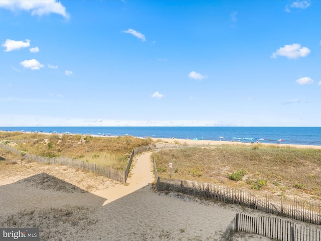 view of water feature with a beach view and fence