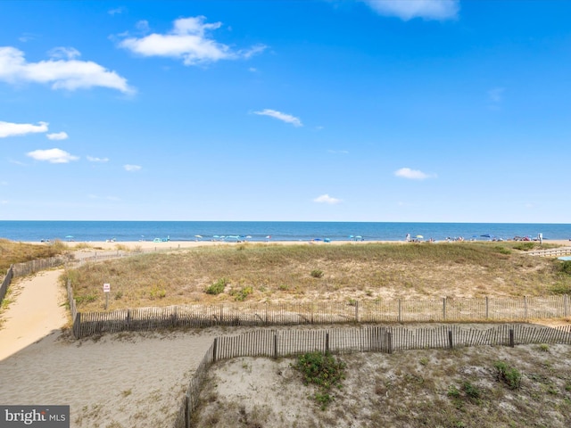 view of water feature with a beach view and fence