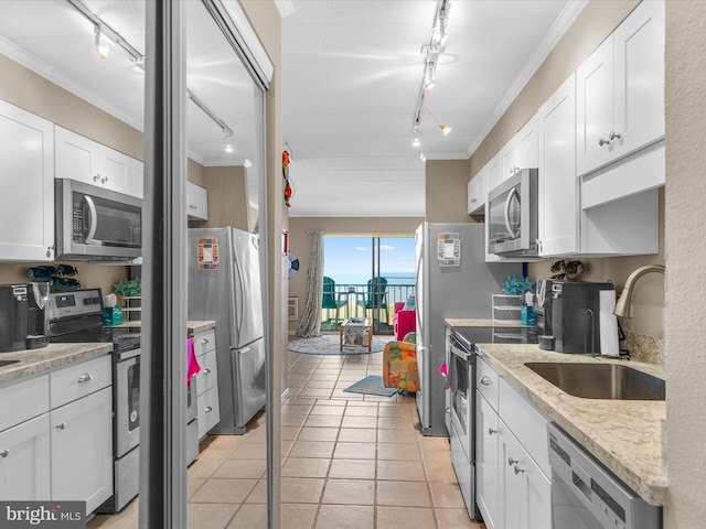 kitchen featuring appliances with stainless steel finishes, ornamental molding, white cabinetry, a sink, and light tile patterned flooring