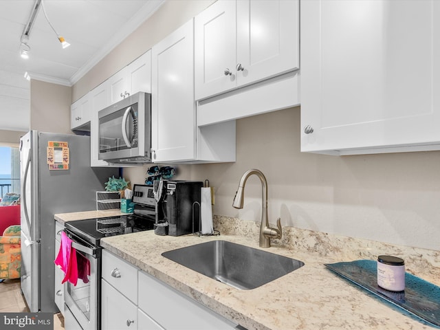 kitchen featuring light stone counters, appliances with stainless steel finishes, ornamental molding, white cabinets, and a sink