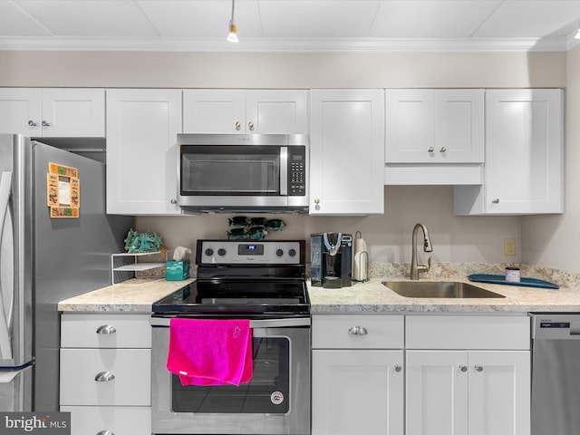 kitchen featuring white cabinets, ornamental molding, stainless steel appliances, and a sink