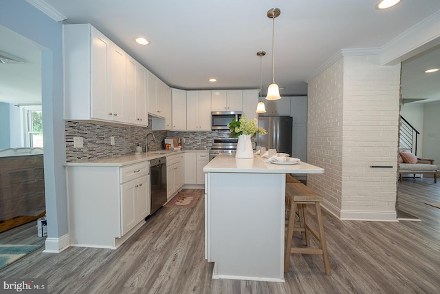 kitchen featuring light hardwood / wood-style flooring, crown molding, a center island, stainless steel appliances, and white cabinetry