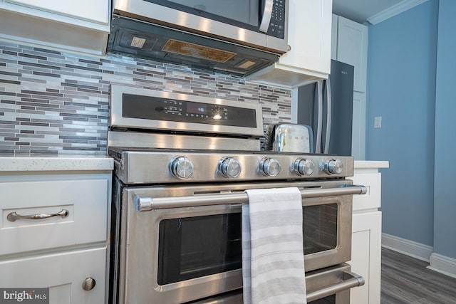 kitchen featuring white cabinetry, backsplash, dark hardwood / wood-style flooring, light stone countertops, and appliances with stainless steel finishes