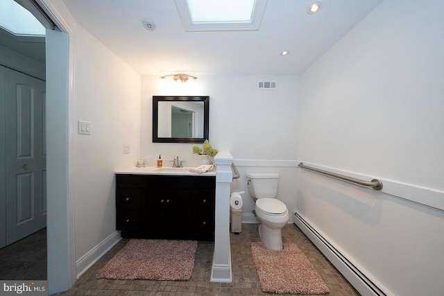 bathroom featuring a skylight, toilet, baseboard heating, and vanity