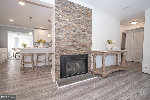 living room with crown molding, light hardwood / wood-style floors, and a fireplace