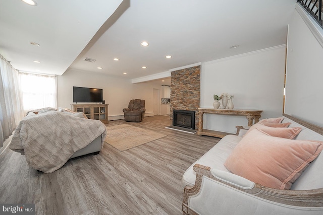 living room featuring a fireplace, ornamental molding, and light hardwood / wood-style flooring